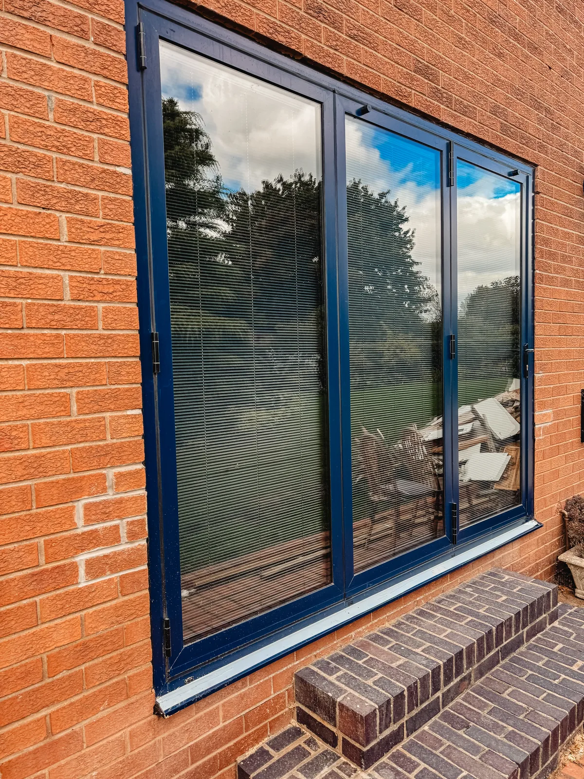 Close-up of aluminium window frames and opening sections above a projecting brick sill